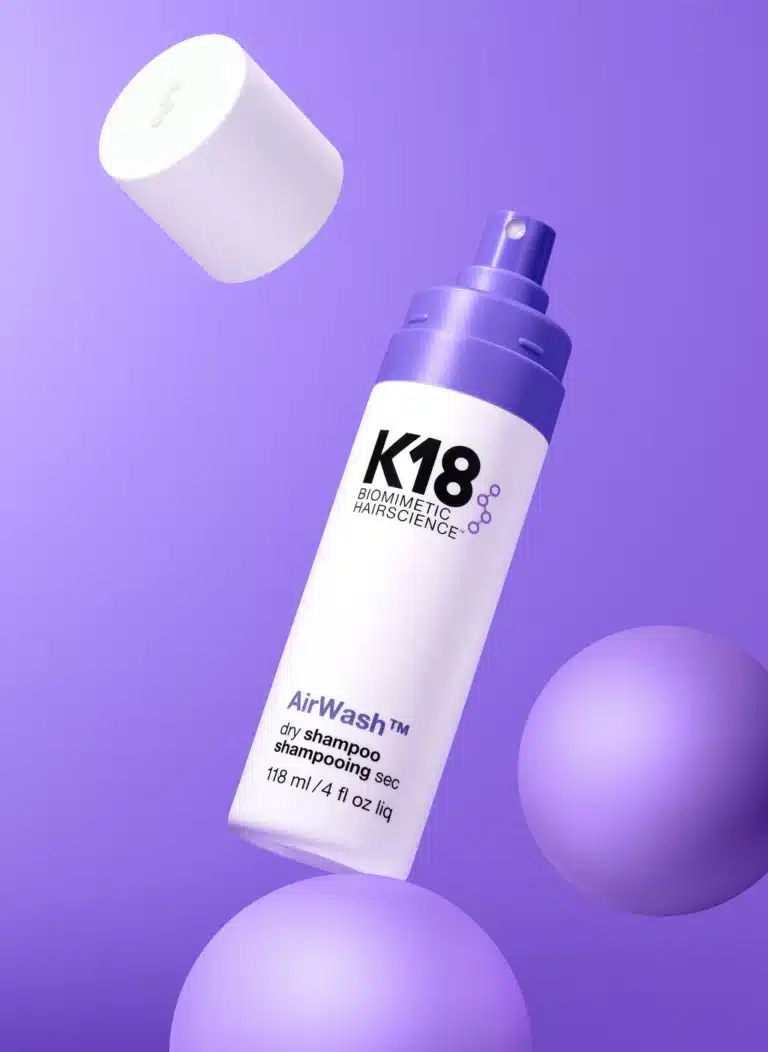 K18 AirWash dry shampoo bottle with cap on a purple background.